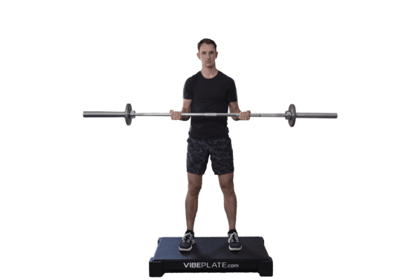 Man standing on VibePlate 2440 while lifting a barbell