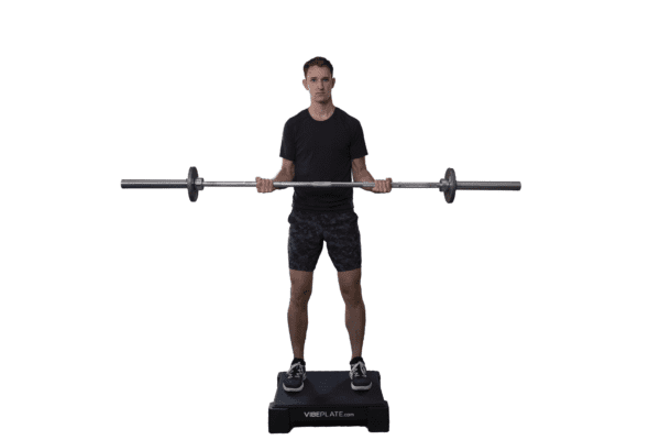 Man standing on VibePlate 2424 while lifting a barbell