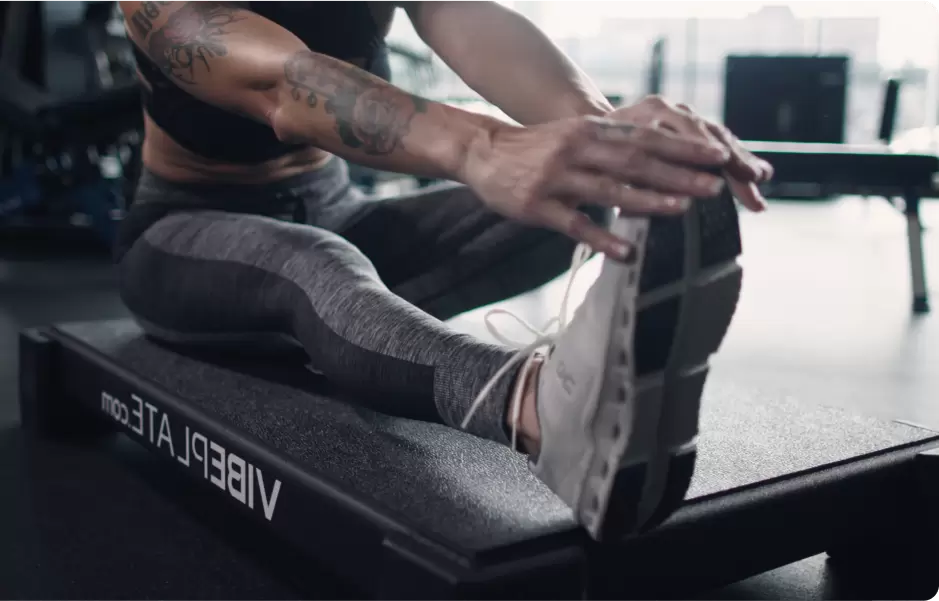 Woman stretching on VibePlate in a gym